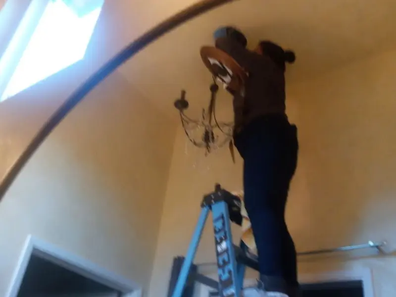 Electrician installing a chandelier in a Chanute residence